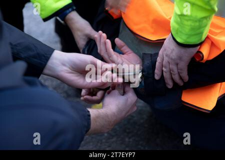 Londra, Regno Unito. 15 novembre 2023. Un manifestante viene ammanettato dalla Met Police per aver bloccato il traffico durante la manifestazione nel centro di Londra. Gli attivisti studenteschi Just Stop Oil si esibiscono su Cromwell Road a Earls Court stamattina presto durante l'ora di punta come parte delle loro tre settimane di marcia lenta. Il gruppo chiede al governo del Regno Unito di sospendere tutte le future licenze per i combustibili fossili e di continuare le proprie azioni fino a quando ciò non avverrà. Credito: SOPA Images Limited/Alamy Live News Foto Stock