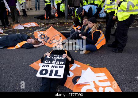 Londra, Regno Unito. 15 novembre 2023. Un manifestante giace a terra per impedire all'agente della polizia Met di arrestarli durante la manifestazione nel centro di Londra. Gli attivisti studenteschi Just Stop Oil si esibiscono su Cromwell Road a Earls Court stamattina presto durante l'ora di punta come parte delle loro tre settimane di marcia lenta. Il gruppo chiede al governo del Regno Unito di sospendere tutte le future licenze per i combustibili fossili e di continuare le proprie azioni fino a quando ciò non avverrà. (Foto di Hesther ng/SOPA Images/Sipa USA) credito: SIPA USA/Alamy Live News Foto Stock