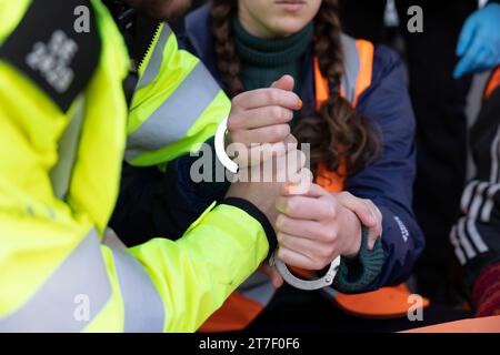 Londra, Regno Unito. 15 novembre 2023. Un manifestante viene ammanettato dalla Met Police per aver bloccato il traffico durante la manifestazione nel centro di Londra. Gli attivisti studenteschi Just Stop Oil si esibiscono su Cromwell Road a Earls Court stamattina presto durante l'ora di punta come parte delle loro tre settimane di marcia lenta. Il gruppo chiede al governo del Regno Unito di sospendere tutte le future licenze per i combustibili fossili e di continuare le proprie azioni fino a quando ciò non avverrà. (Foto di Hesther ng/SOPA Images/Sipa USA) credito: SIPA USA/Alamy Live News Foto Stock