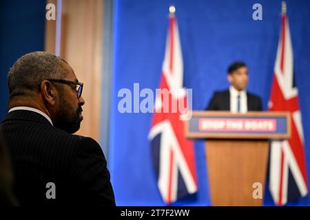 Il Segretario di Stato per l'interno James guarda abilmente mentre il primo Ministro Rishi Sunak tiene una conferenza stampa a Downing Street, Londra, in risposta alla sentenza della Corte Suprema che la politica di asilo in Ruanda è illegale. Il primo ministro ha promesso di fare "tutto il necessario” per fermare gli attraversamenti di piccole imbarcazioni dopo che la Corte suprema ha stabilito la sua politica di punta di rimozione dei richiedenti asilo sui voli di espulsione verso Kigali. Data foto: Mercoledì 15 novembre 2023. Foto Stock