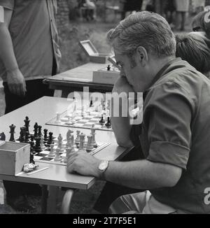 Anni '1960, storico, scacchi, competizione all'aperto, un giocatore maschile che si siede a un tavolo che si concentra sulla sua mossa, Inghilterra, Regno Unito. Foto Stock