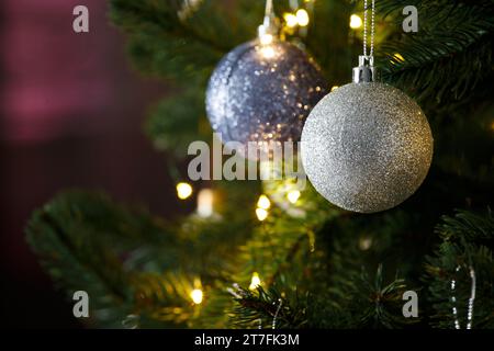 I rami dell'albero di Natale sono decorati con palline di Natale e luci su sfondo scuro, spazio per le copie. Cartolina, modello, banner Foto Stock