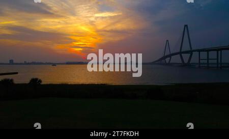Un'immagine mozzafiato di un ponte sagomato sullo sfondo di un tramonto su un tranquillo specchio d'acqua Foto Stock