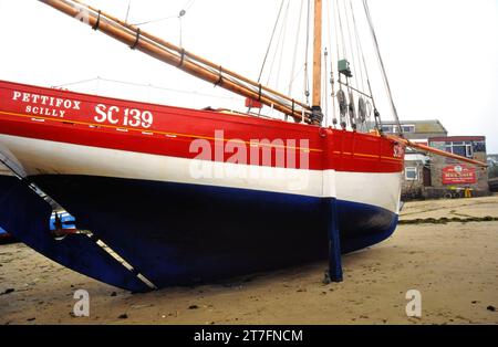 Pettifox, una replica di granchi francesi, è l'ultima barca a vela costruita sulle isole Scilly, vista qui sulla spiaggia del porto di Hugh Town con la Sirenetta Foto Stock