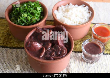 Feijoada tipica cucina brasiliana, fagioli con pancetta di maiale, riso all'arancia e farina, salsa al peperoncino e crackling Foto Stock
