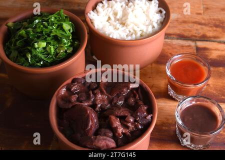 Feijoada tipica cucina brasiliana, fagioli con pancetta di maiale, riso all'arancia e farina, salsa al peperoncino e crackling Foto Stock