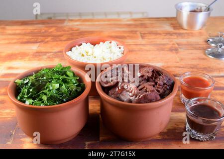 Feijoada tipica cucina brasiliana, fagioli con pancetta di maiale, riso all'arancia e farina, salsa al peperoncino e crackling Foto Stock