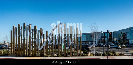 Insegne artistiche metalliche del centro commerciale Liffey Valley, Dublino, irlanda, con cielo azzurro e parcheggio in vista. Foto Stock