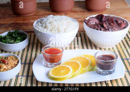 Feijoada tipica cucina brasiliana, fagioli con pancetta di maiale, riso all'arancia e farina, salsa al peperoncino e crackling Foto Stock