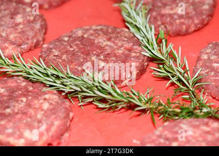 hamburger crudo carne macinata con rosmarino pronto per cuocere Foto Stock