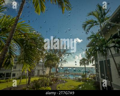 Grand Cayman, Isole Cayman, 25 maggio 2023, vista delle gocce di pioggia su una finestra che si affaccia sul Mar dei Caraibi Foto Stock