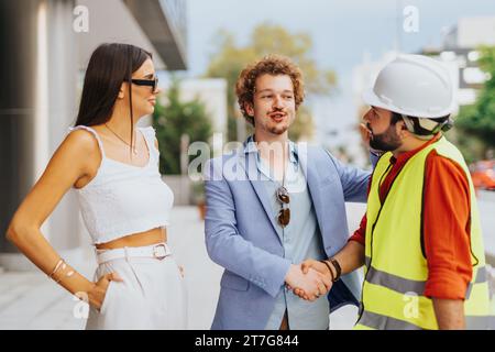 Diversi architetti discutono di documenti di progetto, esaminano progetti e creano un brainstorming di design sostenibile per un nuovo edificio aziendale. Foto Stock