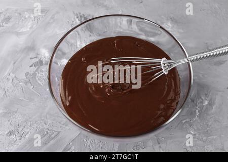 Frullare in un recipiente con panna al cioccolato su un tavolo grigio, vista dall'alto Foto Stock