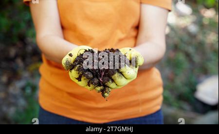 Un contadino tiene in mano i vermi rossi più agghiaccianti Foto Stock