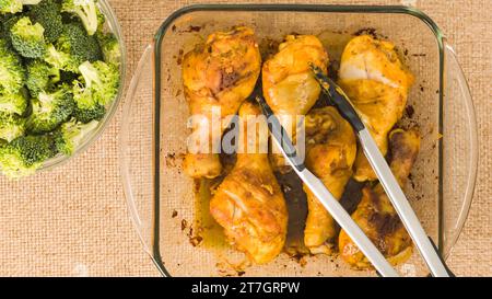 Cosce di pollo al forno in un piatto da forno in vetro da vicino su un tavolo da cucina, stendere piatti Foto Stock