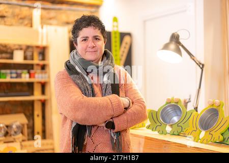 Ritratto di una donna matura artigiana in un laboratorio in piedi e sorridente in un laboratorio Foto Stock