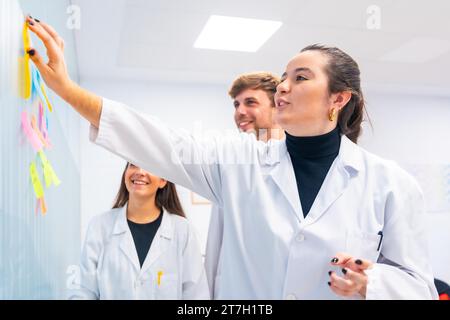Tre giovani biologi durante un incontro di brainstorming in un laboratorio di ricerca sul cancro Foto Stock