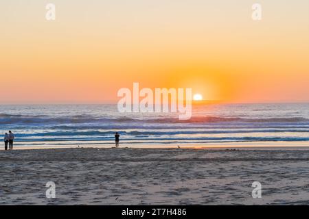 Surfers Paradise - 21 settembre 2023; l'alba sulla spiaggia di Surfers Paradise con persone insignificanti ai bordi delle acque lontane. Foto Stock