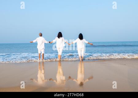 Felice coppia indiana anziana con una bellissima giovane figlia che posa e si gode una vacanza in spiaggia. Foto Stock