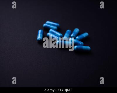 Capsule di aminoacidi su sfondo di carta scura. Messa a fuoco morbida. Primo piano. Copia spazio. Foto Stock