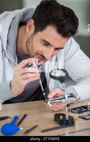 uomo che smonta lo smartphone in un'officina di riparazione Foto Stock