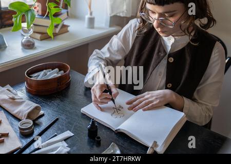 Disegnatore di cartoni animati, pittore, istruttore di disegno disegnando animazioni con inchiostro di disegno nel libro di schizzi Foto Stock