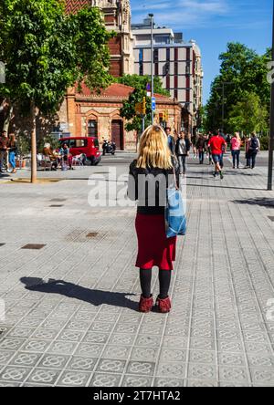 Barcellona, Catalogna, Spagna 01 maggio 2017 - Bionda turista a Barcellona che controlla il suo telefono per le indicazioni stradali su una strada trafficata Foto Stock