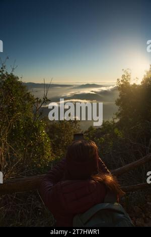 Una donna scatta foto con il suo cellulare dell'alba in montagna. Foto Stock