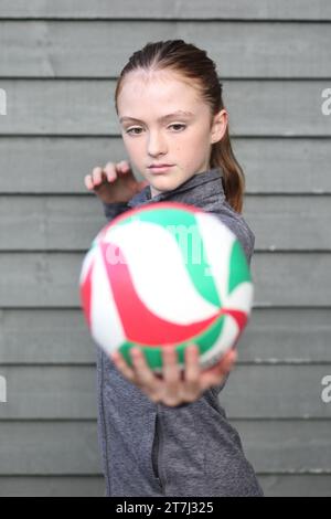 La ragazza adolescente guarda in basso la pallavolo mentre la tiene pronta a servire Foto Stock