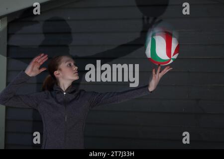 La ragazza adolescente pratica tiri di pallavolo, che stanno per servire con la palla sulla punta delle dita Foto Stock