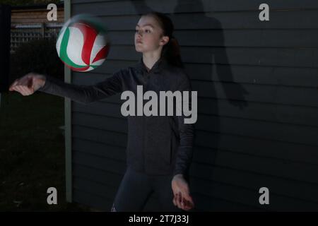 La ragazza adolescente pratica pallavolo tiri di pallavolo movimento sfocato della palla Foto Stock