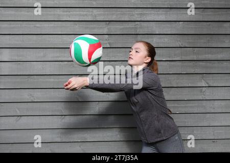 La ragazza adolescente pratica i tiri di pallavolo, un tiro di scavo con gli occhi puntati sulla palla Foto Stock