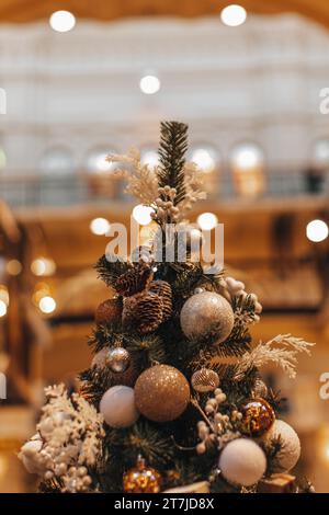 Dettagli magici e accoglienti, luci bokeh dorate, sfondo da favola. Albero di Natale decorato con palle di Natale e coni di pino. Foto Stock