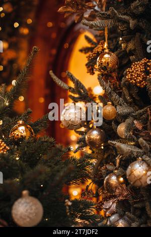 Composizione di Capodanno in un interno natalizio. Ramo verde dell'albero di Natale decorato con ghirlande magiche d'oro e balli di Natale. Foto Stock