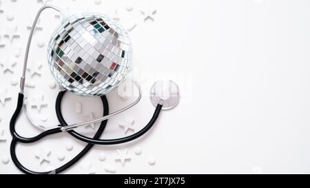 Banner medico natalizio.primo piano di stetoscopio, disco ball, stelle e pillole su sfondo bianco, vista dall'alto, piatto, copia spazio.anno nuovo o Natale par Foto Stock