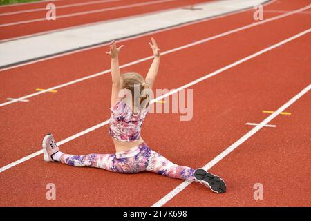 Ragazza in un legging rosa che fa le spaccature allo stadio Foto Stock