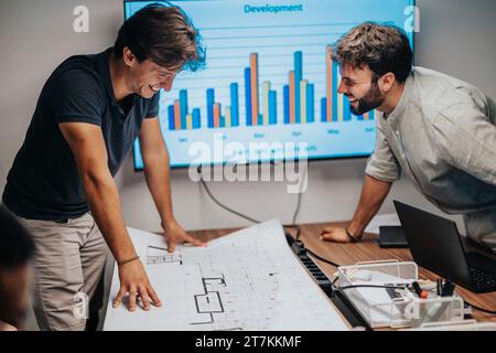 I professionisti multiculturali collaborano in una sala riunioni, discutendo progetti architettonici, pianificando progetti e dimostrando il successo del lavoro di squadra. Foto Stock