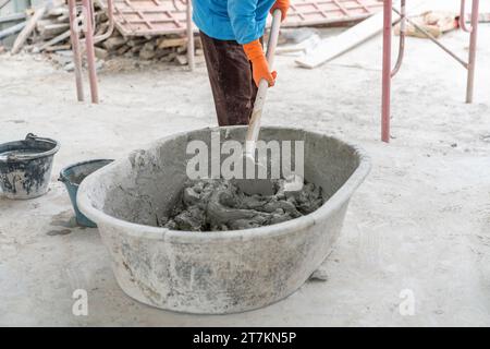 Il lavoratore mescolare il cemento in una provetta di plastica in cantiere. Foto Stock