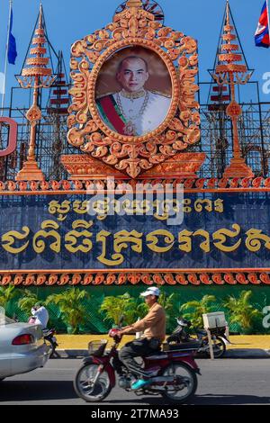 Phnom Penh, Cambogia, 2014. Un uomo in moto passa davanti al ritratto ufficiale del re Norodom Sihamoni di fronte al Parco del Palazzo reale Foto Stock