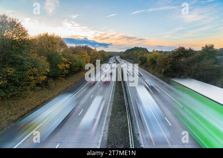 Auto in rapido movimento sulla UK Motorway al tramonto. Concetto di strade trafficate e congestione o traffico nelle ore di punta Foto Stock