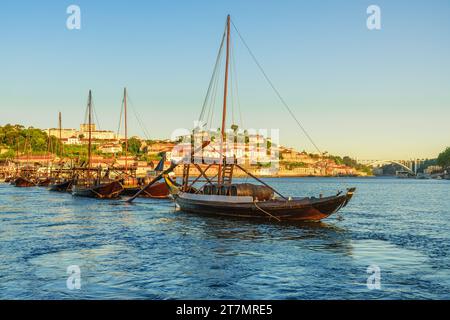 Barche da carico tradizionali portoghesi rabelo sul fiume Douro con la città di Porto sullo sfondo all'alba, in Portogallo. Destinazione di viaggio Foto Stock