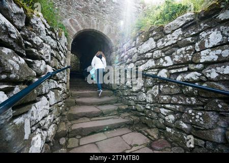 Due persone che saliscono le vecchie scale di pietra in una rovina abbandonata verso il castello di Dunnottar in Scozia, Regno Unito, Europa Foto Stock