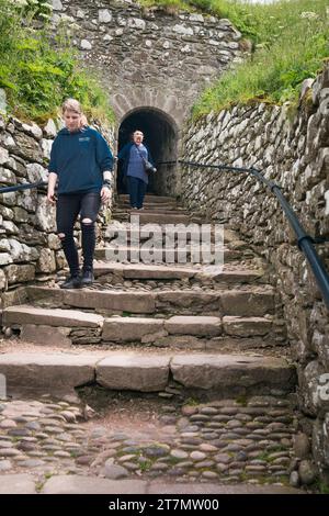 Due persone camminano sulle vecchie scale di ciottoli su una rovina abbandonata al castello di Dunnottar, Stonehaven, Scozia, Regno Unito, Europa Foto Stock