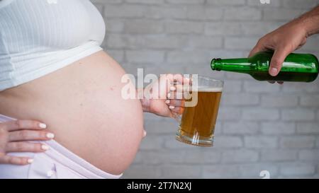 Un uomo che versa birra per una donna incinta. Foto Stock