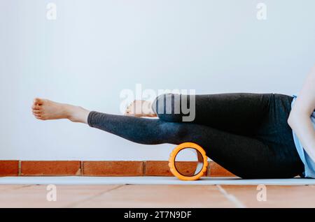 Donna che LO fa con massaggio a rilascio miofasciale su un rullo di sughero Foto Stock