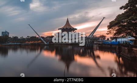All'alba del Kuching State Assembly Building e del Darul Hana Bridge lungo il fiume Sarawak Foto Stock
