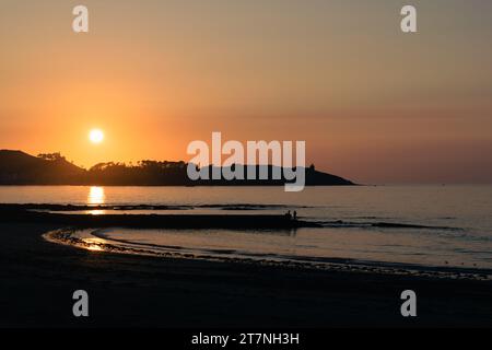 Splendida immagine del tramonto al frangiflutti di Playa América con Baiona sullo sfondo e il sole che tramonta dietro la montagna di Nigran. Galizia Foto Stock