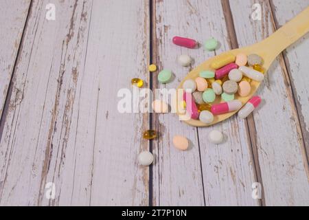 Pillole, compresse e capsule di medicina farmaceutica assortite su cucchiaio di legno. Foto Stock