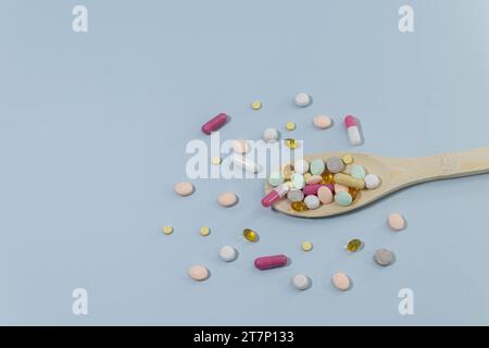 Pillole, compresse e capsule di medicina farmaceutica assortite su cucchiaio di legno. Foto Stock