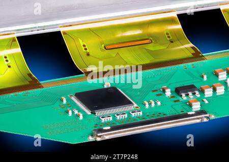 Primo piano su una scheda a circuito stampato con microchip, condensatori o resistori. Microchip neri su circuito stampato verde con parte flessibile in plastica all'interno di un pannello LCD. Foto Stock